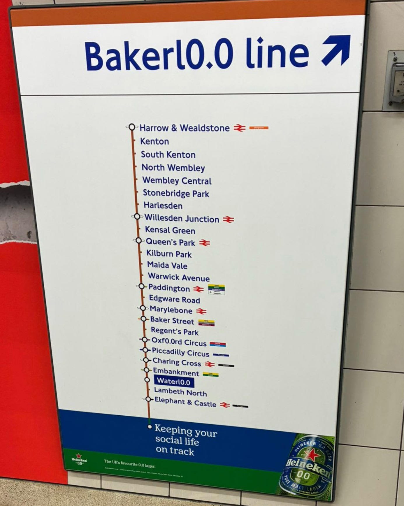 A sign pointing to the Bakerloo line, showing all its stops. Instead of saying “Bakerloo line”, “Oxford Circus” and “Waterloo” stations, the “oo” has been replaced with 0.0. At the bottom of the map it says “Keeping your social life on track, Heineken 0.0. The UK’s favourite 0.0 lager.” A sign pointing to the Bakerloo line, showing all its stops. Instead of saying “Bakerloo line”, “Oxford Circus” and “Waterloo” stations, the “oo” has been replaced with 0.0. At the bottom of the map it says “Keeping your social life on track, Heineken 0.0. The UK’s favourite 0.0 lager.”