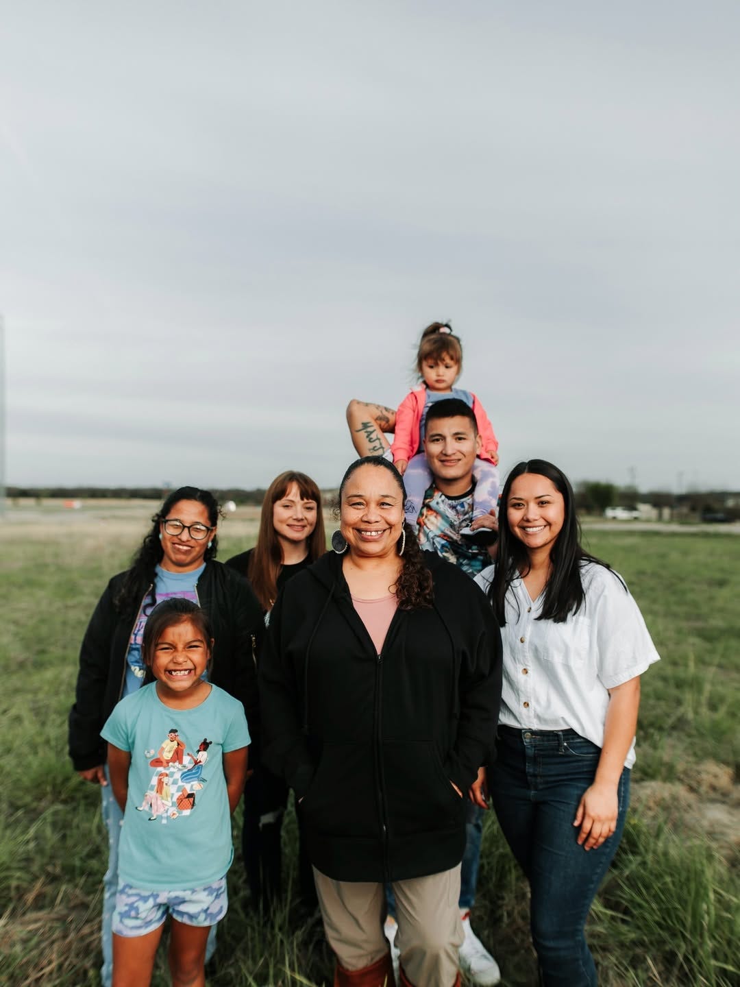 Chef Crystal Wahpepah standing outside in a green field with her family