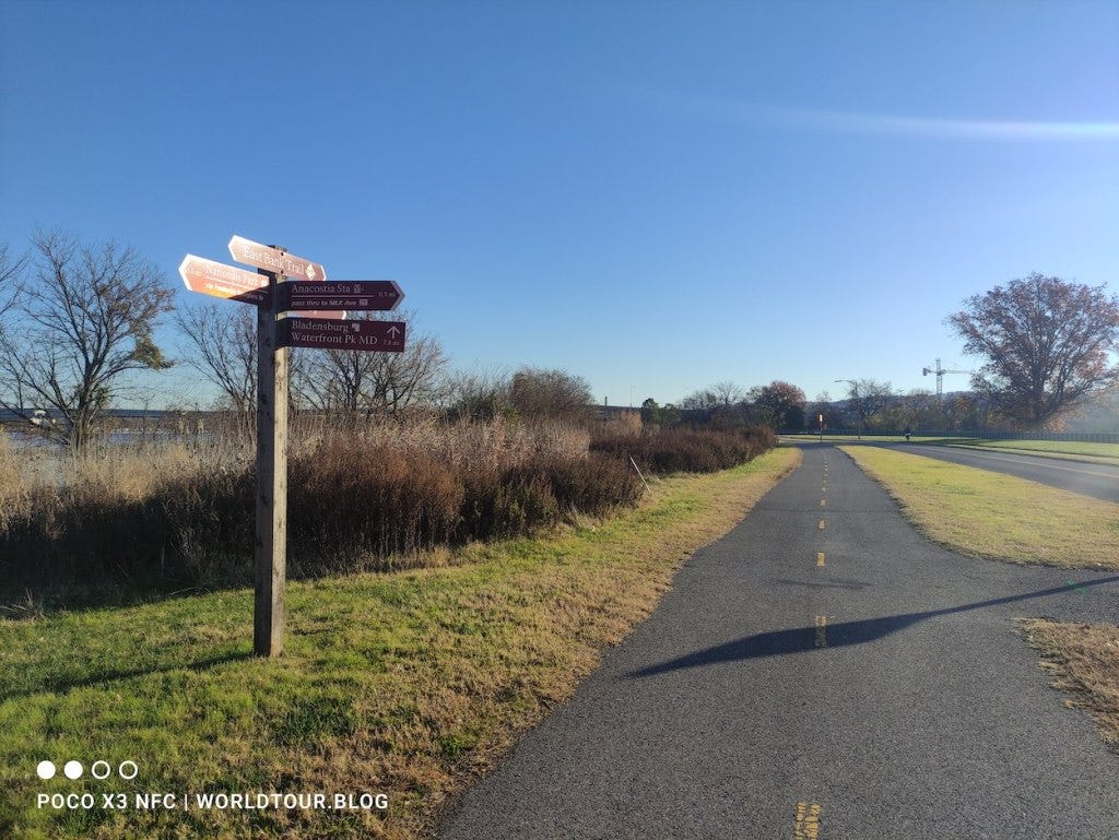 A sign post marks the start and finish. The tarmacced trail runs off into the distance, with a yellow line marking the centre.