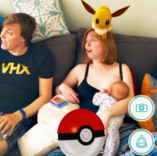 Screenshot taken in Pokemon GO in 2016 of me nursing my kid on the couch with an Eevee on my head, taken by Taylor Skillin