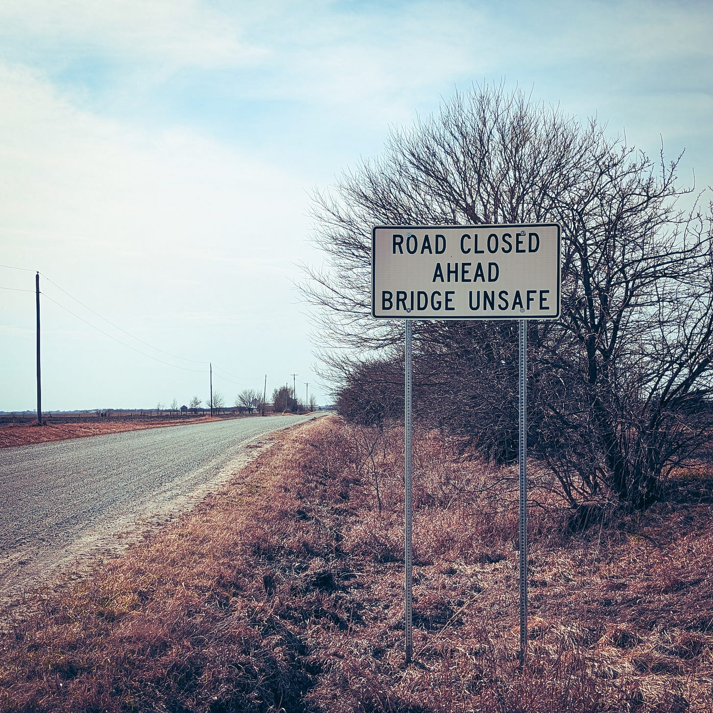 a sign on a gravel road that says "road closed, bridge unsafe"