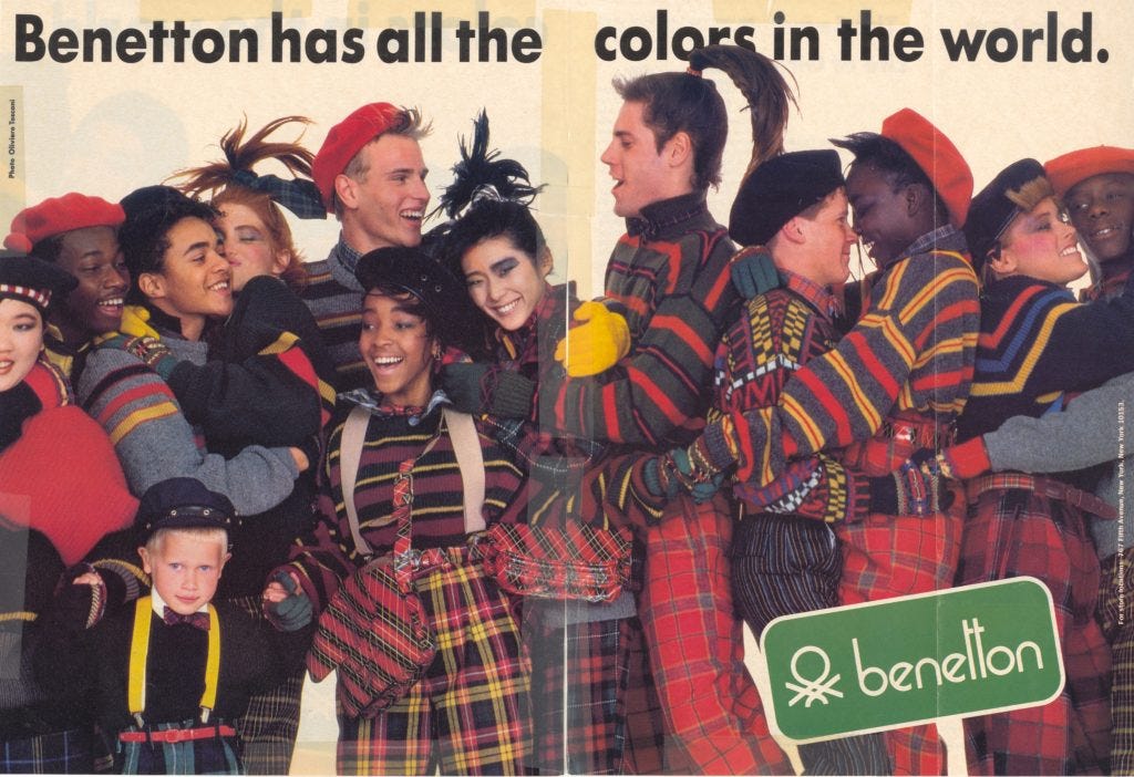 Benetton magazine advertisement featuring about a dozen people of different races and ages. They are all wearing Benetton clothing and hugging one another. 
