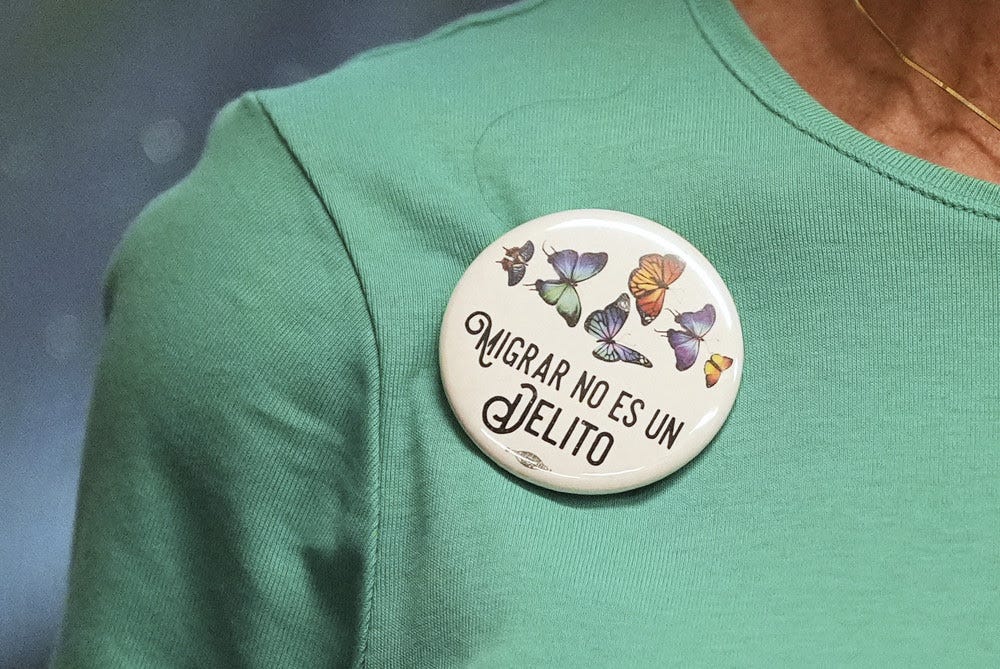 A Cuban immigrant advocate wears a button reading in Spanish "Migrating is not a crime," during a press conference to denounce a recent Supreme Court decision which allows the Trump administration to strip humanitarian parole protection for more than 500,000 immigrants from Cuba, Haiti, Nicaragua, and Venezuela. 