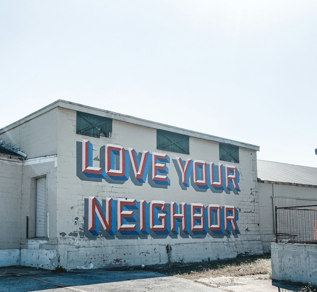 a large sign on the side of a building that says love your neighbor