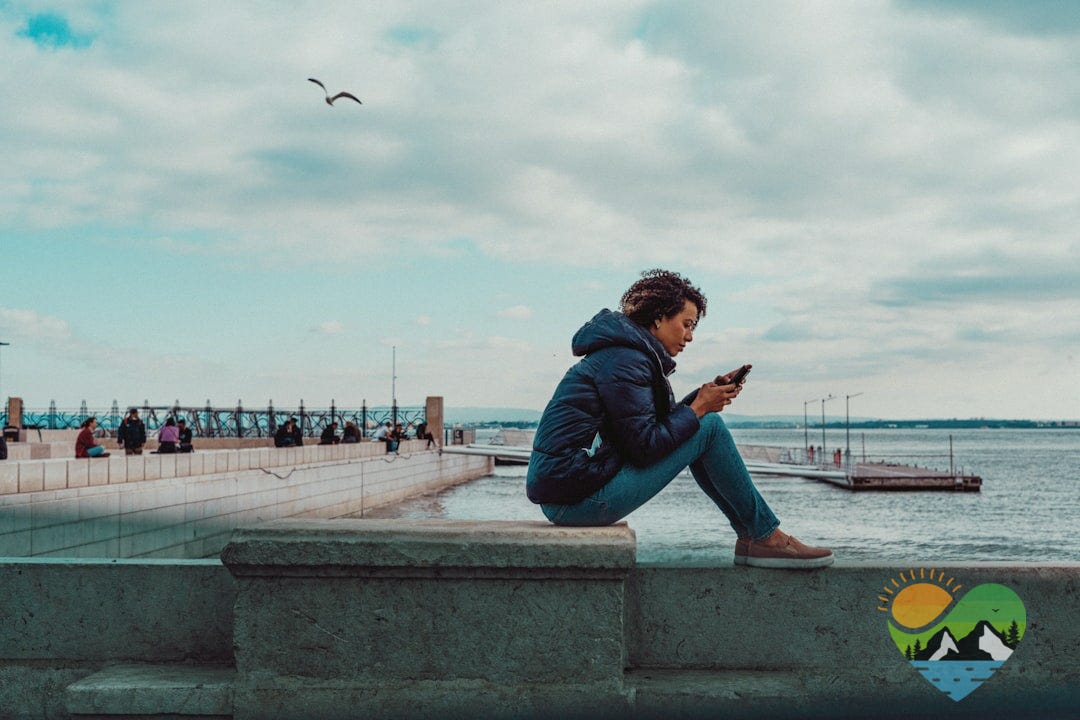 a man sitting on a ledge looking at his cell phone