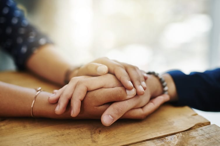 Person wrapping two hands around another person's hand Person wrapping two hands around another person's hand