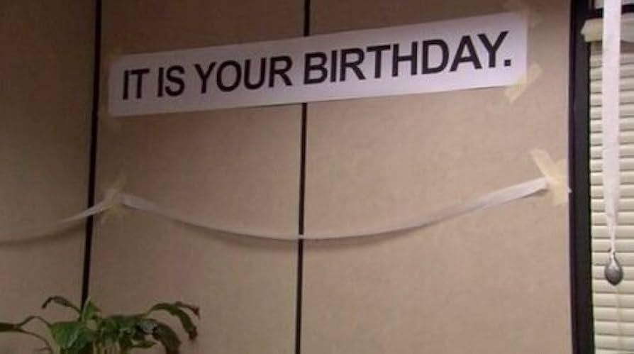 A screenshot from "The Office" with a banner on an office wall that reads "IT IS YOUR BIRTHDAY."
