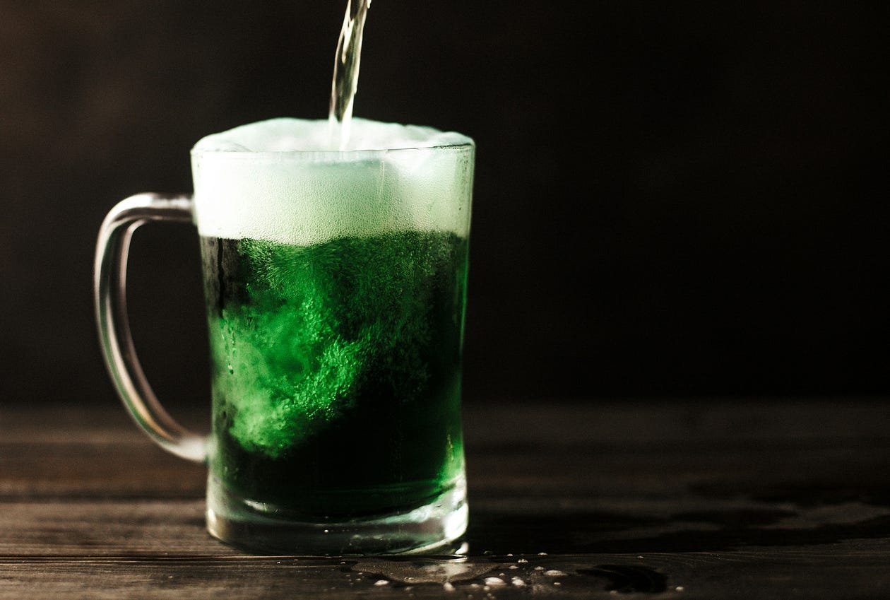 a glass mug of green foamy beer