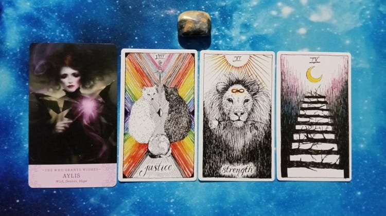 Elle Qui and Wild Unknown Tarot cards with gray and yellow stone on starry blue background