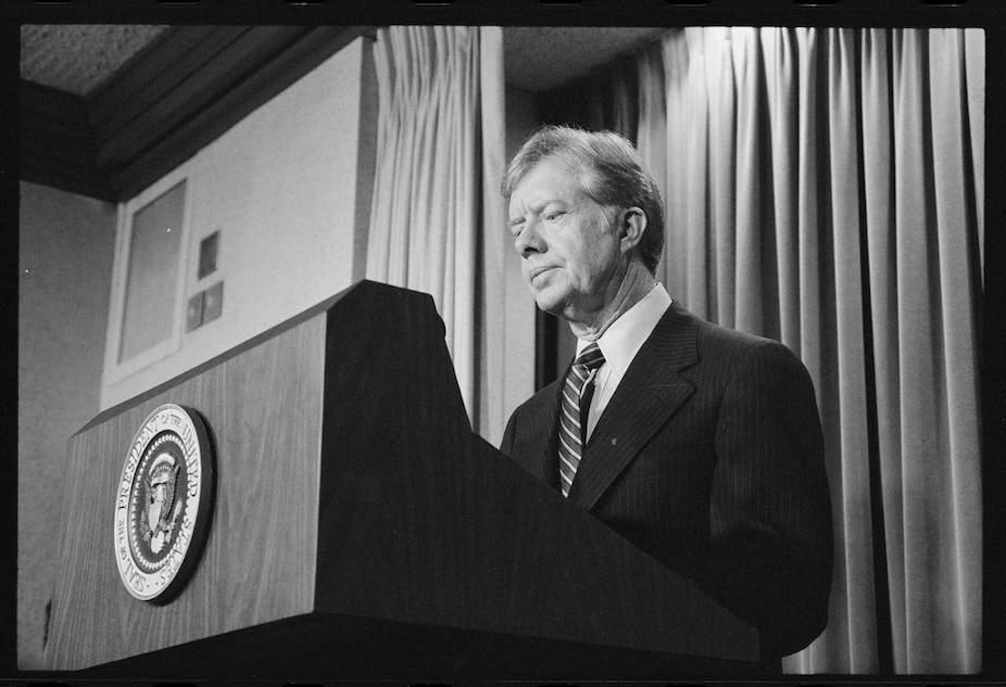 A man in a suit standing behind a podium. A man in a suit standing behind a podium.