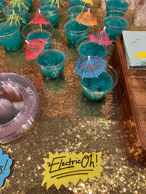 left: the bench in front of the cruise backdrop with "Never Been Shipped" strung above, center: a teal mocktail with a little umbrella in it and a sign that says "ElectricOh!", right: the outside of Tombolo at night