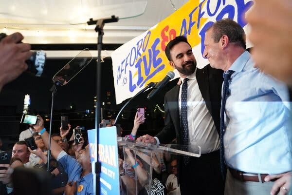Zohran Mamdani, left and Brad Lander, right, embrace on a stage at an election night party. A sign above Mr. Mamdani, who is wearing a black suit, says Afford to Live.