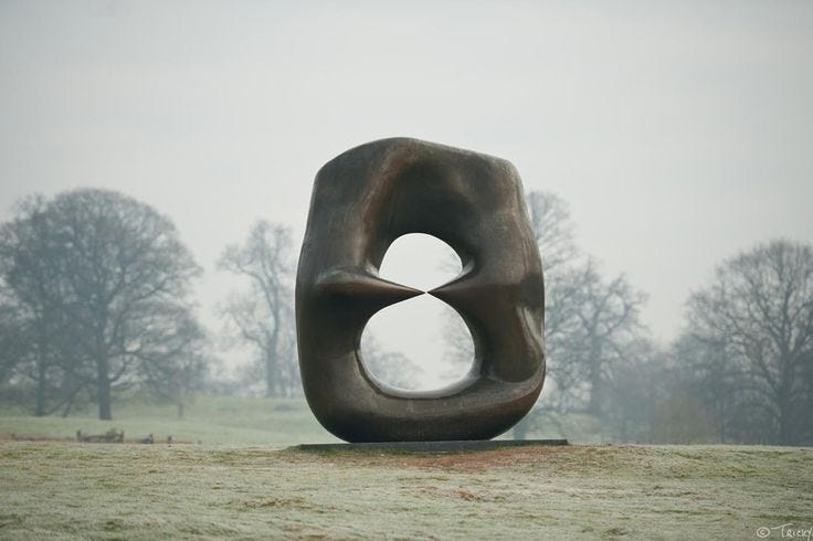 This may contain: a sculpture in the middle of a grassy field with trees in the backgroud