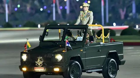AFP via Getty Images Myanmar's junta chief military Min Aung Hlaing arrives to deliver a speech during a ceremony to mark the country's Armed Forces Day in Naypyidaw in 2024. He is wearing a military outfit and standing in an open top green car. AFP via Getty Images Myanmar's junta chief military Min Aung Hlaing arrives to deliver a speech during a ceremony to mark the country's Armed Forces Day in Naypyidaw in 2024. He is wearing a military outfit and standing in an open top green car.