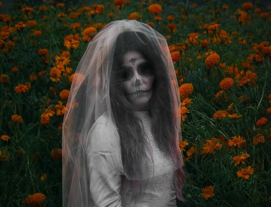 a woman in a white dress and veil standing in a field of flowers a woman in a white dress and veil standing in a field of flowers