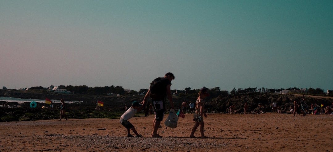 A couple of people walking across a sandy beach A couple of people walking across a sandy beach