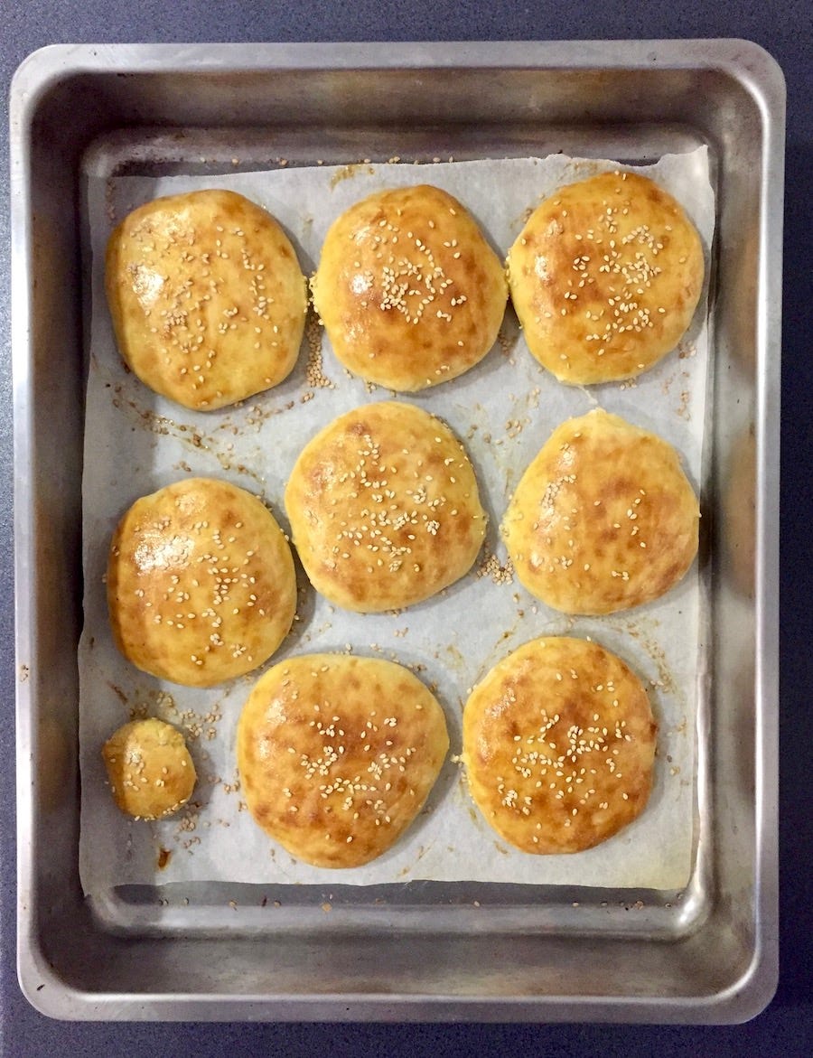 photo of baked burger bun with sesame seeds on top, fresh out from the over, in the over dish