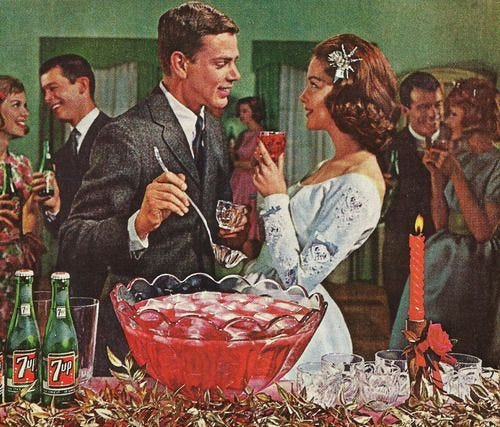 This may contain: a man and woman standing in front of a cake with candles on it, surrounded by other people This may contain: a man and woman standing in front of a cake with candles on it, surrounded by other people