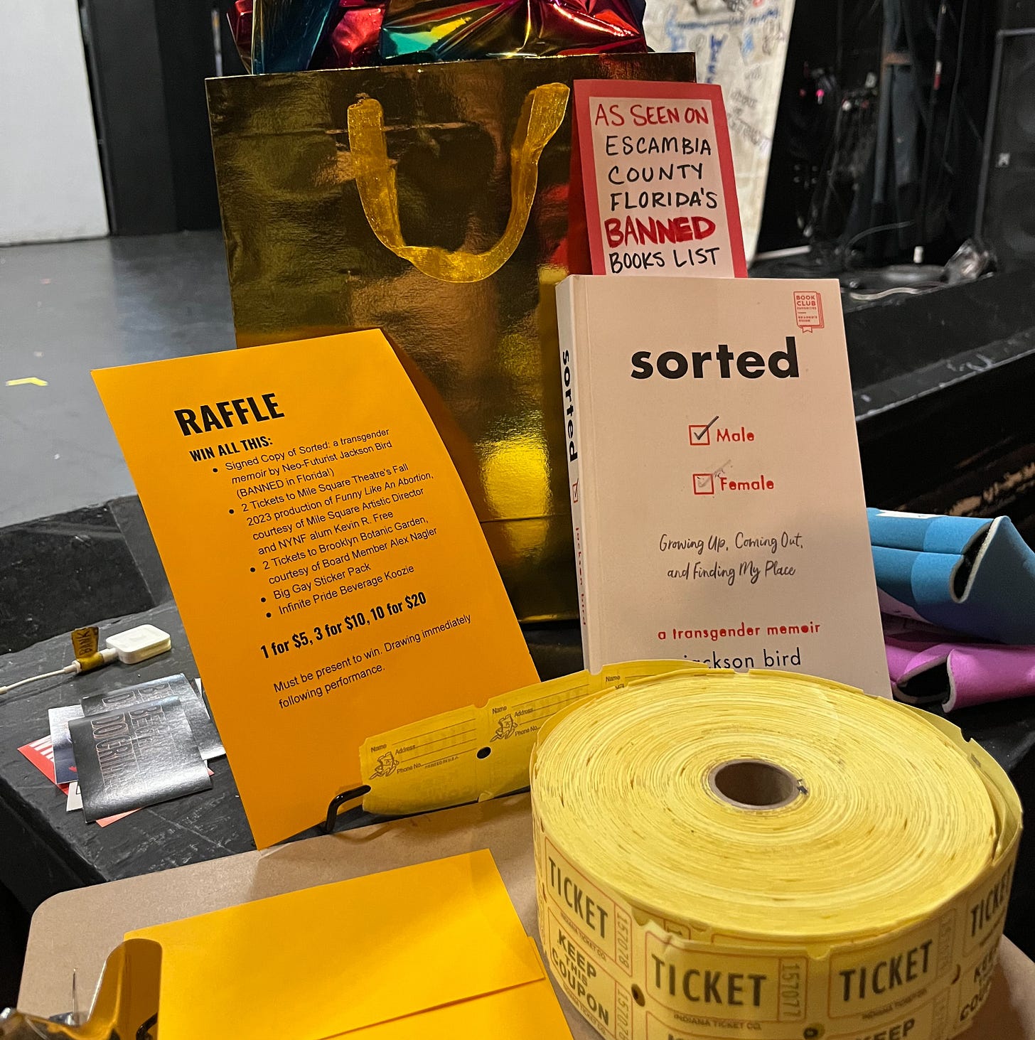 A copy of Jackson Bird's book sorted, in a display for a raffle, with a sign sticking out of it that reads "As seen on Escambia County, Florida's Banned Books List" A copy of Jackson Bird's book sorted, in a display for a raffle, with a sign sticking out of it that reads "As seen on Escambia County, Florida's Banned Books List"