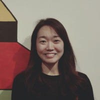Suky smiling in front of a mural