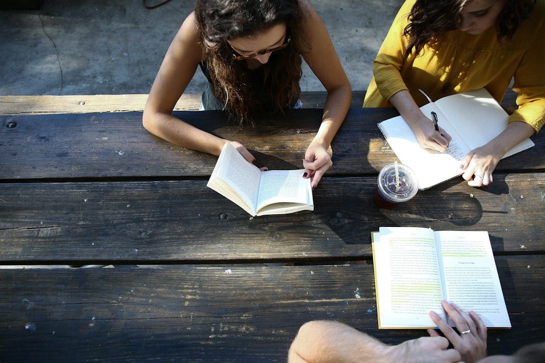 woman reading book while sitting on chair woman reading book while sitting on chair