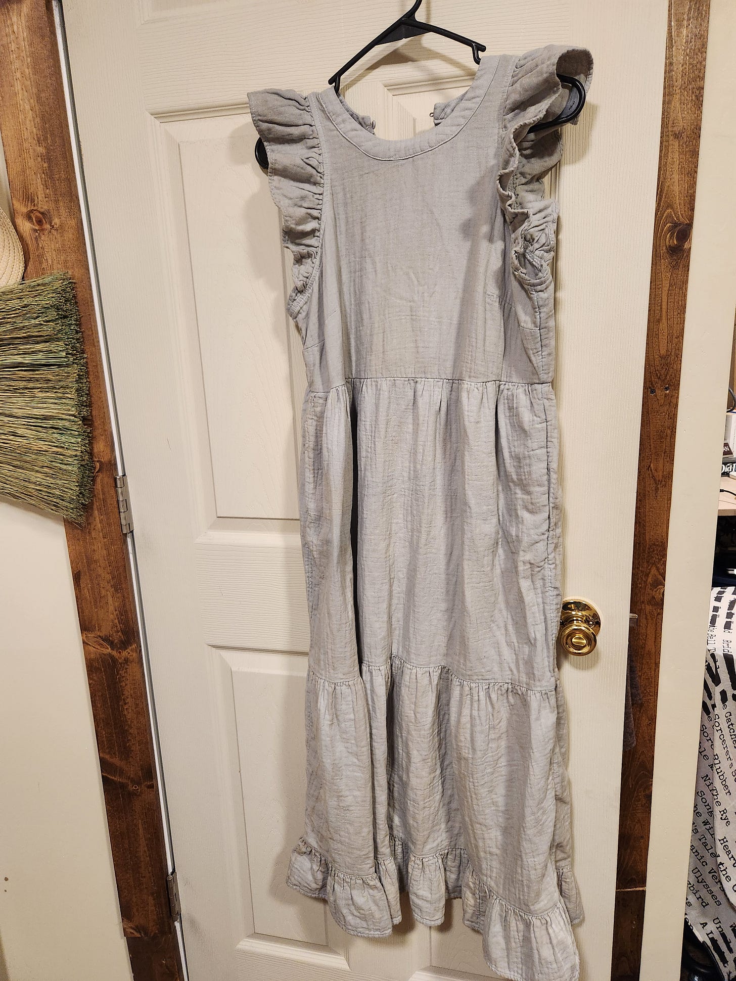 A formerly white dress, now light blue, is hanging up. It has a tiered skirt and ruffled cap sleeves.