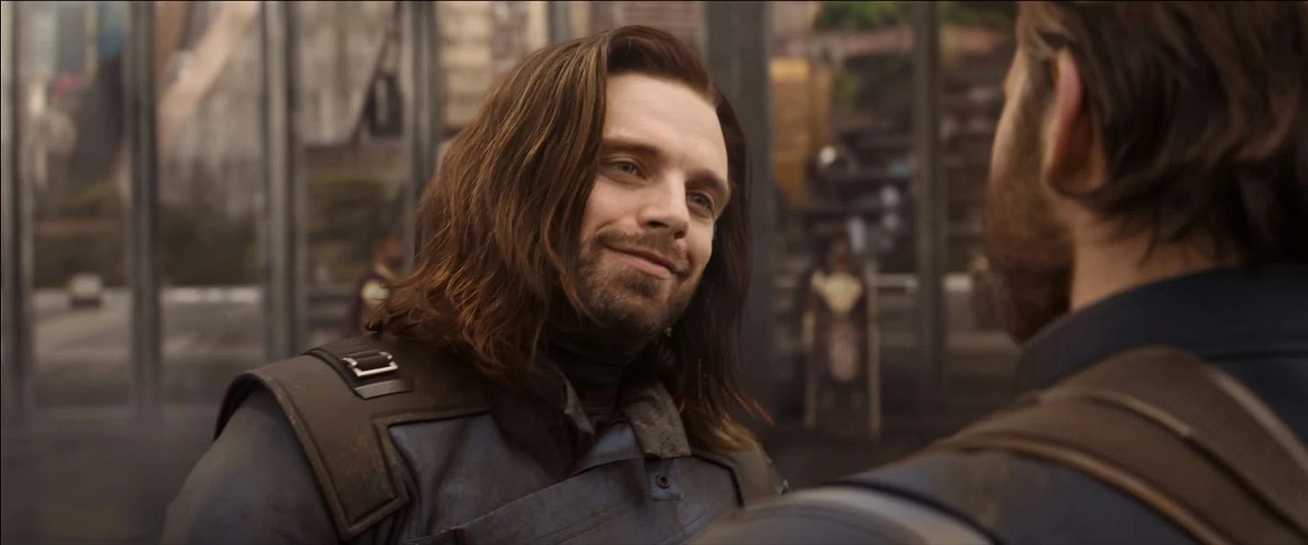 Bucky Barnes in Avengers: Infinity War, his luscious locks looking like he just got a blowout. He has a pretty full beard and smiles at Steve.