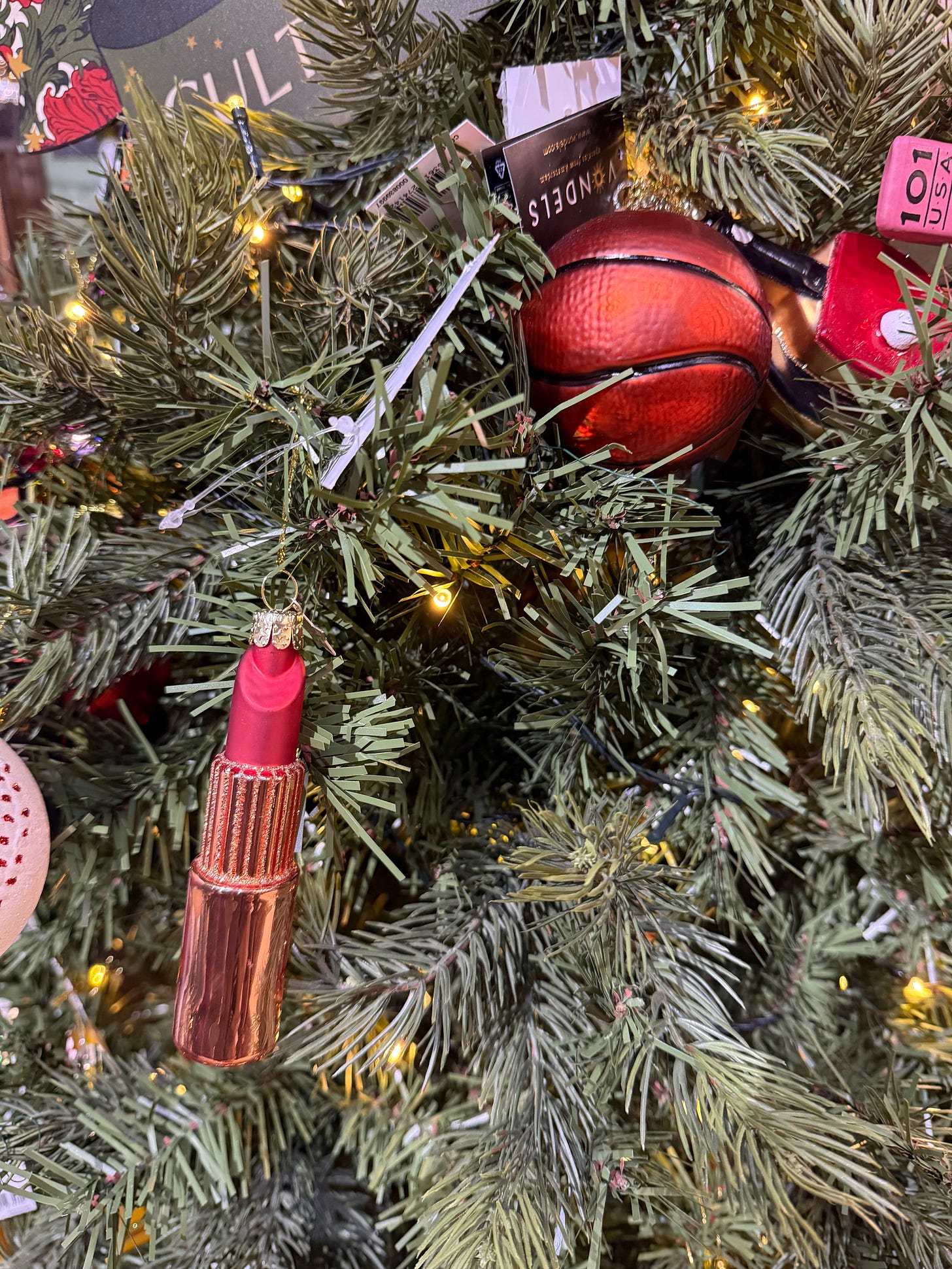 close up of a Christmas tree with glass ornaments of a basketball and tube of red lipstick close up of a Christmas tree with glass ornaments of a basketball and tube of red lipstick
