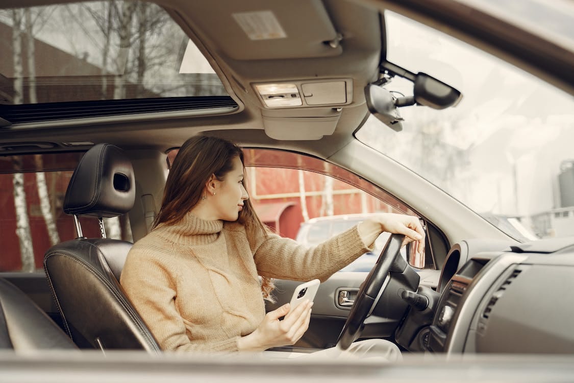 Free Adult woman sitting in car and using smartphone Stock Photo