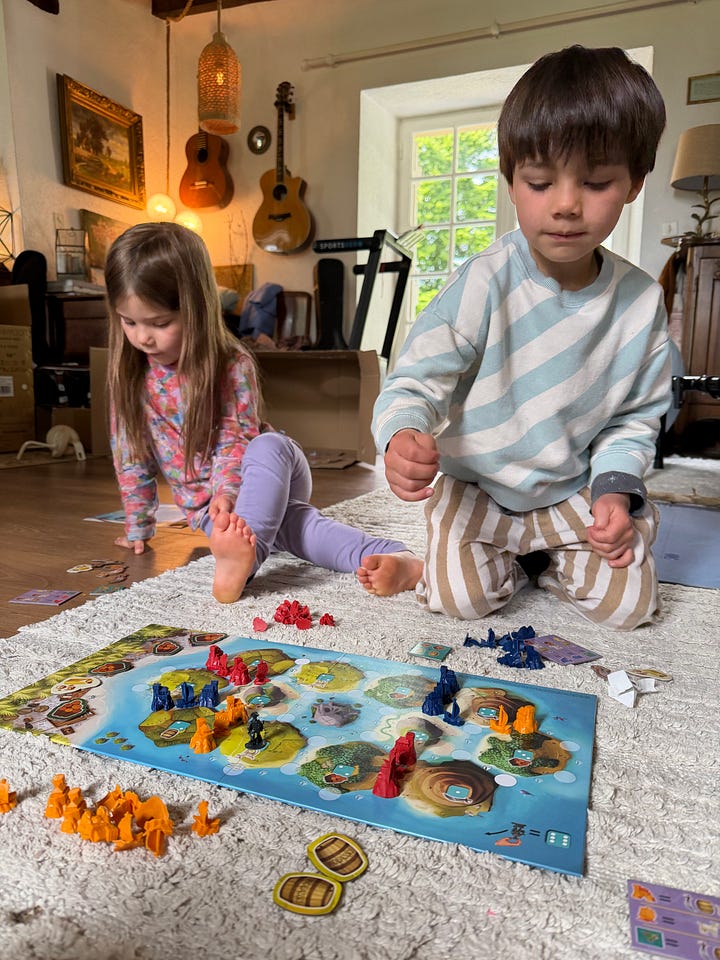 Two children playing a board game and two children painting.