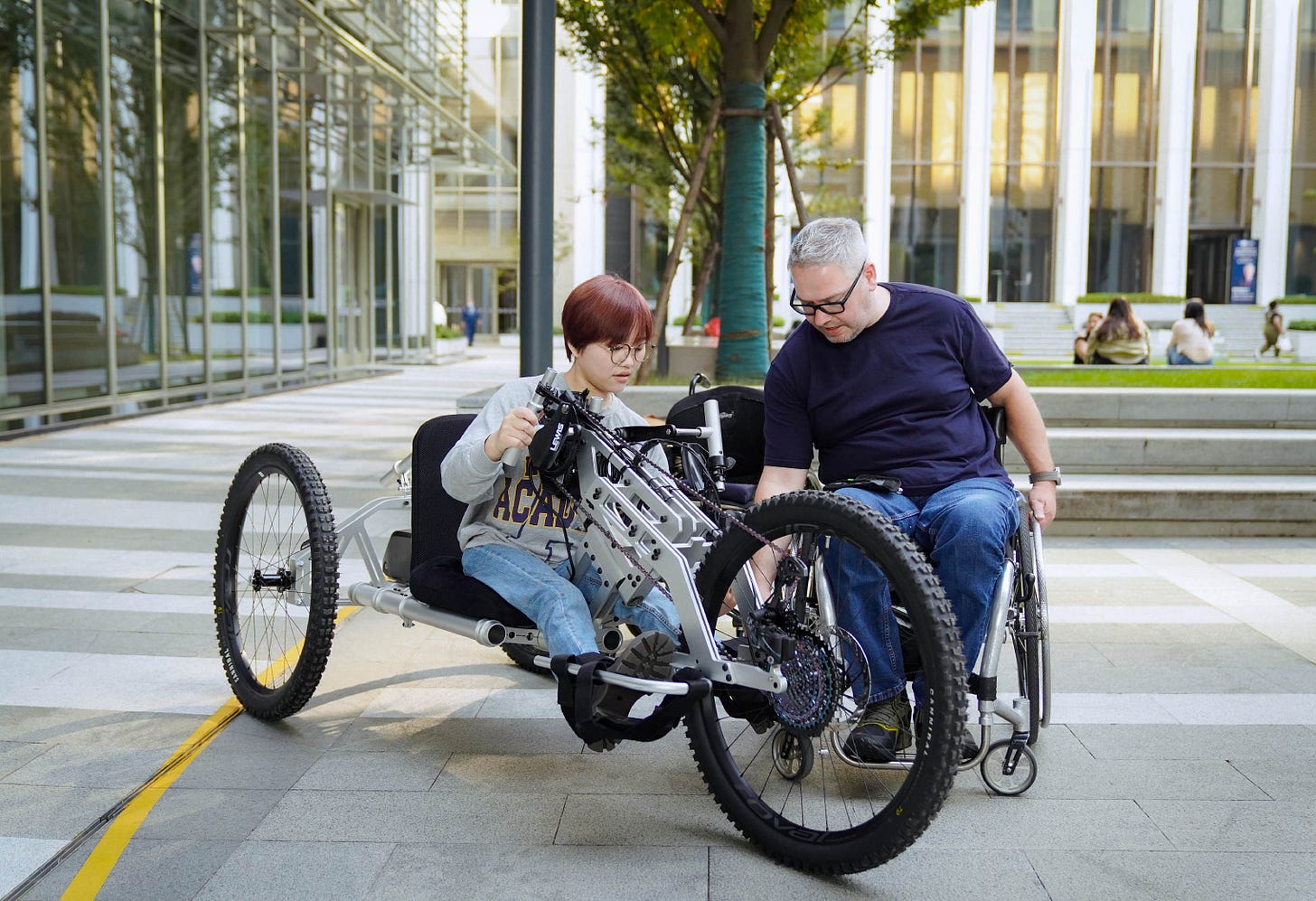 Noël et une collegue ou etudiante en train de tester le VTT a main open source sur un campus universitaire.