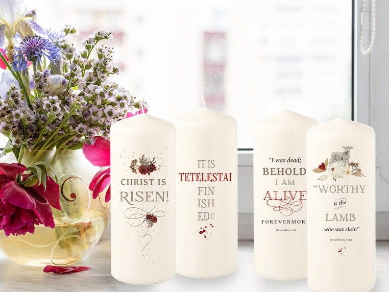 May include: Three white pillar candles with red and gold floral designs and text. The candles are labeled 'Christ is Risen!' 'It is Tetelestai Finished!' and 'I was dead; Behold I am Alive Forevermore Revelation 1:18' and 'Worthy is the Lamb who was slain' Revelation 5:12.