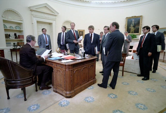 President Ronald Reagan sits at his Oval Office desk with senior advisers gathered around during a national security meeting in 1983, following the Marine Barracks bombing in Beirut.