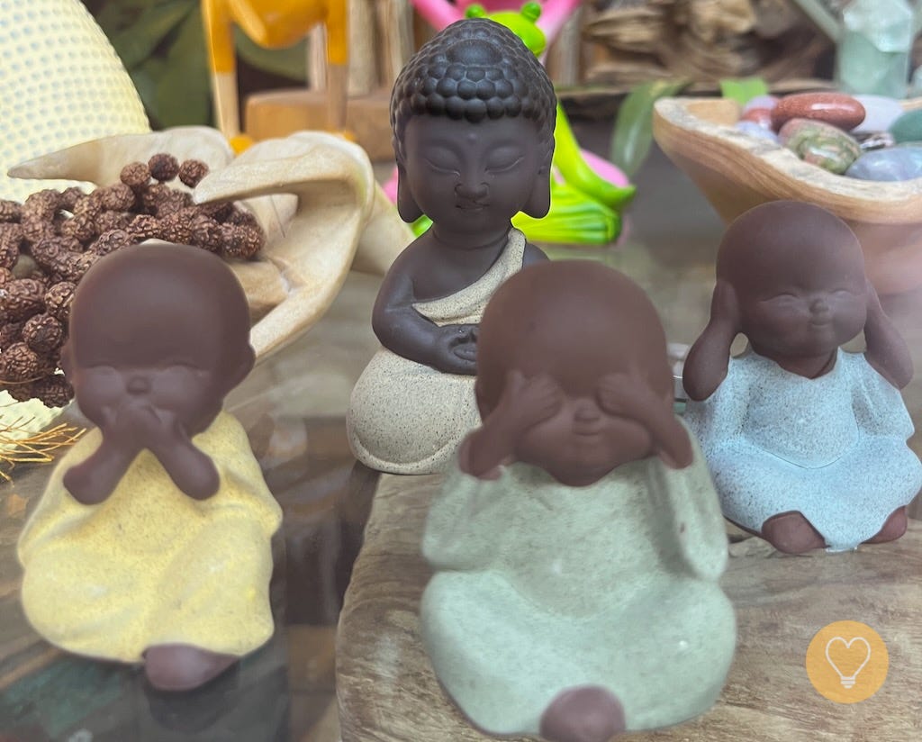 Author’s photo of miniature Buddha figurines in a storefront in Montreal for article: The Brain Keeps the Score, the Body Takes the Hits, the Mind Spins the Stories