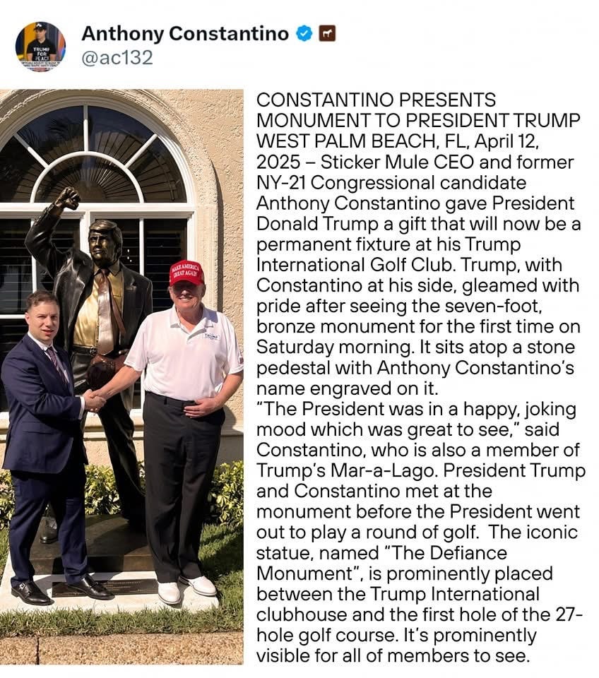 Photo of Donald Trump and Anthony Constantino shaking hands beside a tall bronze statue of Trump in a suit and raised fist pose. The statue stands in front of a building at Trump’s golf club, with a stone pedestal engraved with Constantino’s name.