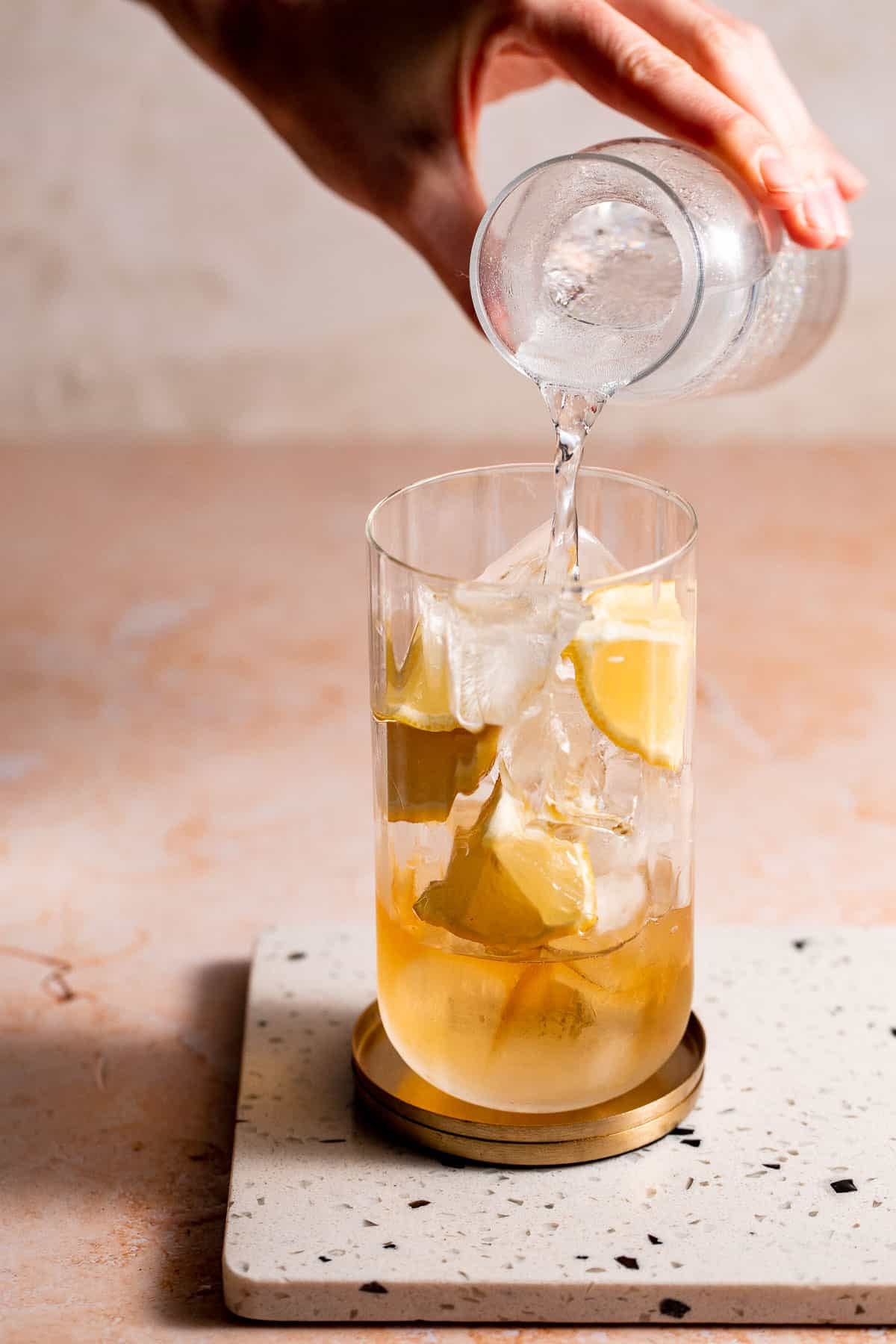 7UP pouring into a highball glass filled with ice and whiskey.