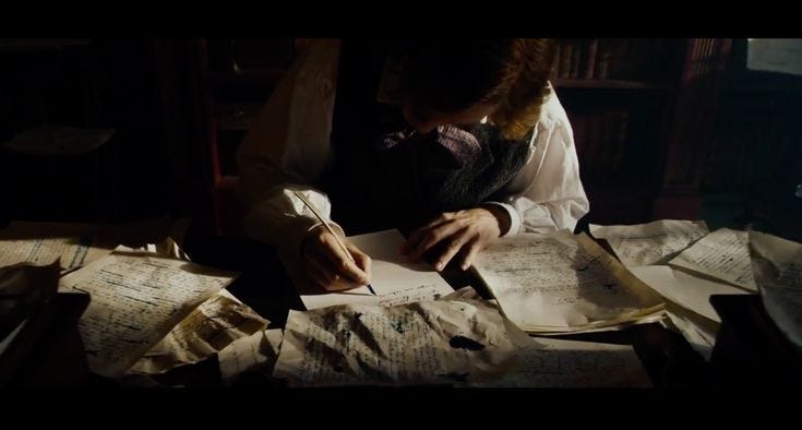 This may contain: a person sitting at a table with lots of papers on top of it and writing