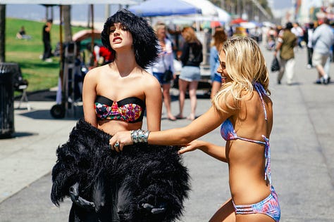 Barbara Palvin and Ashley Hart on set, laughing and posing with a gorilla suit—pulling it on, peeling it off, and mixing fashion with absurdity during the Mambo Goddess campaign shoot.