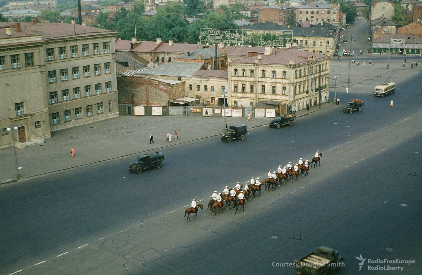 An unexpected sight in the 1950s Soviet landscape: a line of horses occupying the center lane of a street. An unexpected sight in the 1950s Soviet landscape: a line of horses occupying the center lane of a street.
