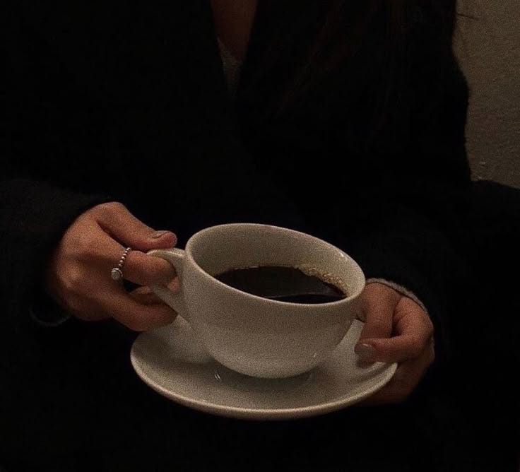 This may contain: a woman holding a cup of coffee in her hands