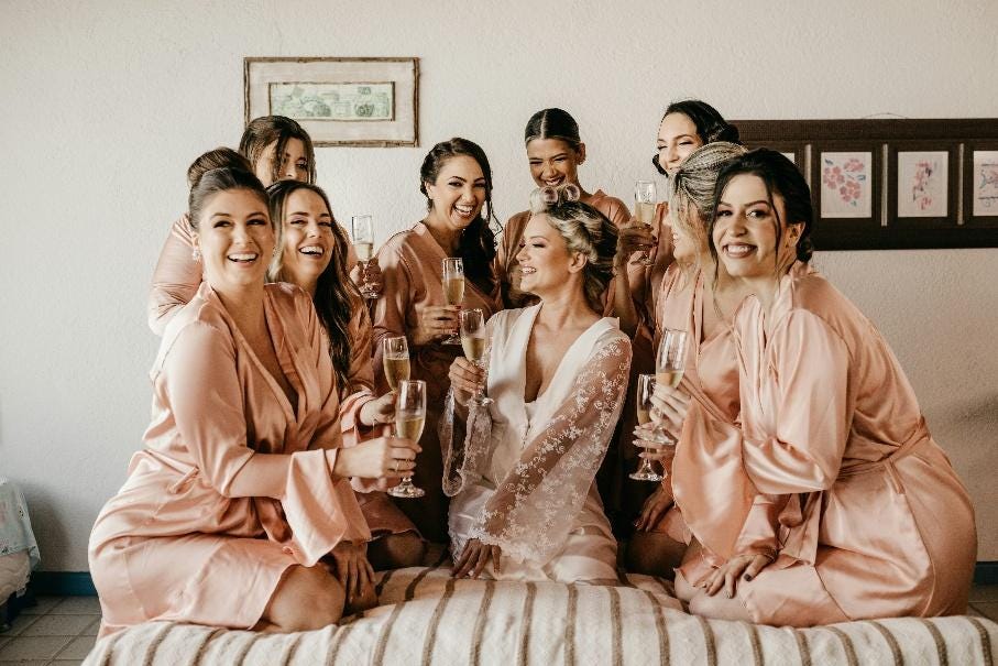 A group of women sitting on a bed with champagne glasses

AI-generated content may be incorrect.