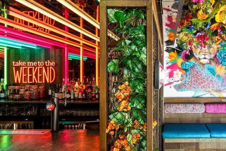 This may contain: the inside of a bar with colorful lights and artwork on the wall behind it,