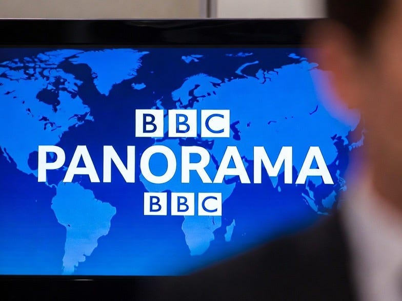 A documentary image of a BBC Panorama broadcast screen with a blurred figure in a suit. A documentary image of a BBC Panorama broadcast screen with a blurred figure in a suit.