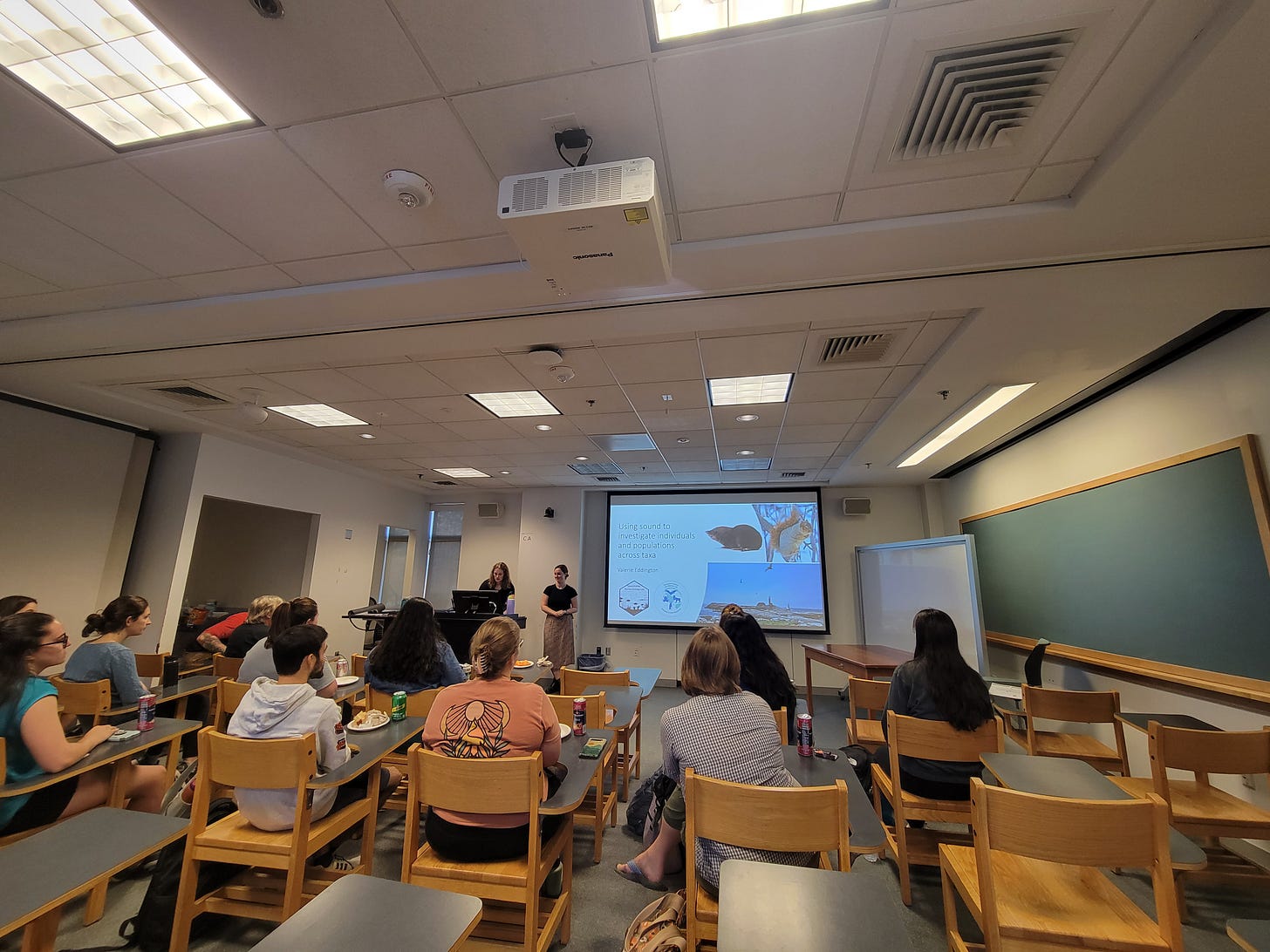 Valerie Eddington in front of screen of slideshow. Audience in desks in the foreground