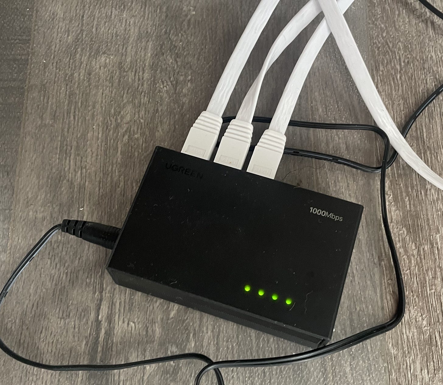 Beating The Tide CLS deep dive image of a home UGREEN 1000 Mbps Ethernet switch with multiple white network cables, illustrating the jump from Wi-Fi to wired speed and tying into Celestica’s 800G data-center theme.