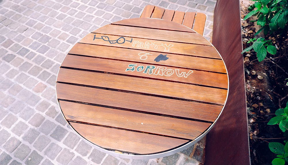 an outdoors table with "party and sorrow" graffiti on it.