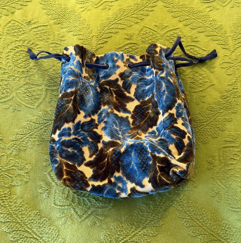 May include: A blue and brown velvet drawstring bag with a floral pattern.