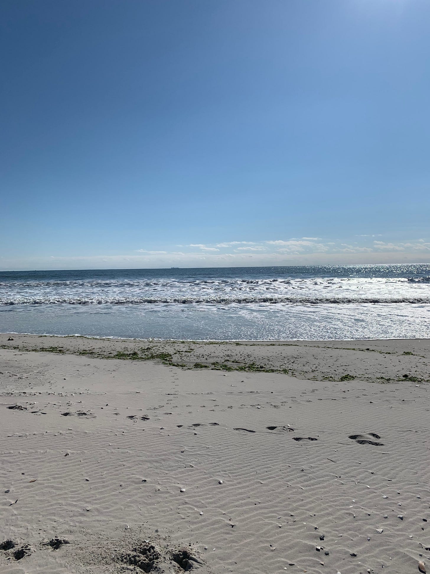 A beach. Sand leading into surf leading into blue sky. A beach. Sand leading into surf leading into blue sky.