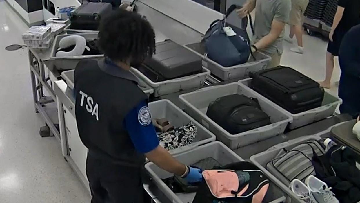 A TSA officer slipping his hand into a purse as it goes through a checkpoint at Miami International Airport. He was charged with grand theft and organized schemes to defraud. A TSA officer slipping his hand into a purse as it goes through a checkpoint at Miami International Airport. He was charged with grand theft and organized schemes to defraud.