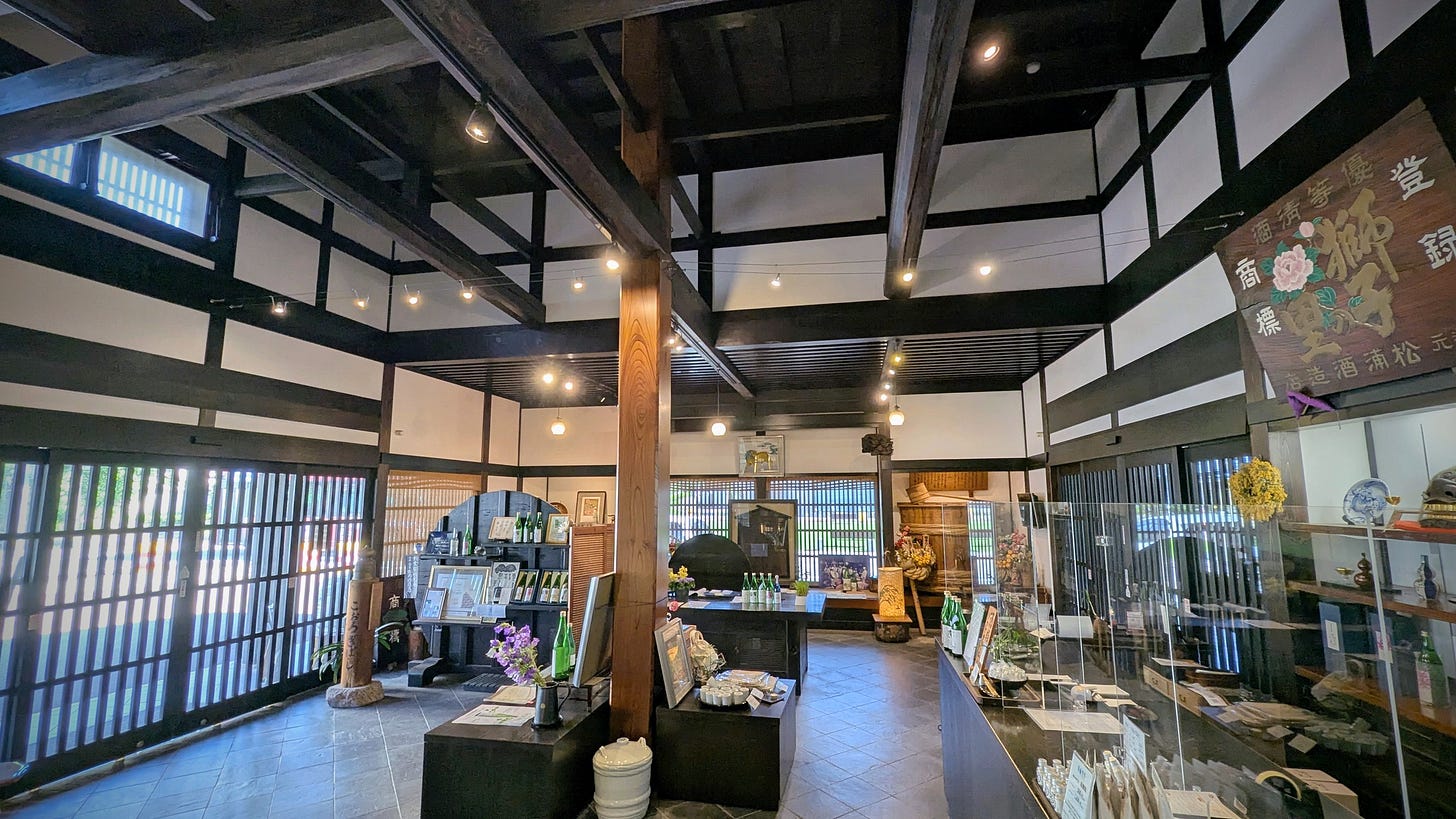 An airy sake shop with white walls, dark wood beams, and high ceilings.